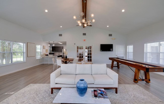 A spacious living room with a white sofa and a pool table.