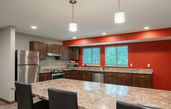 a kitchen with a granite counter top island and stainless steel appliances. Fridley, MN Georgetown on the River Apartments