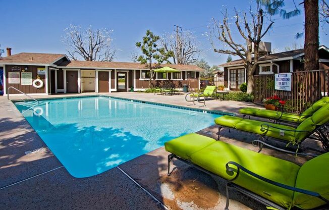 a swimming pool with green chairs around it