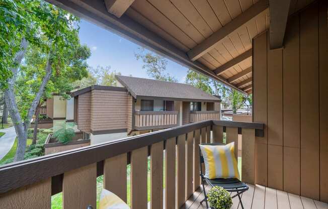 a balcony with two chairs and a house in the background