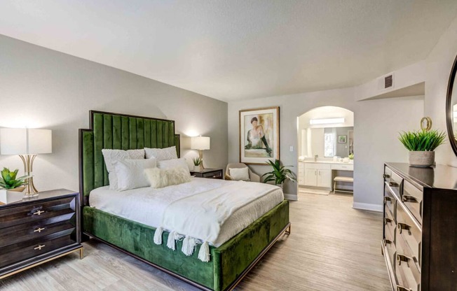 a bedroom with a green bed and a bathroom in the background