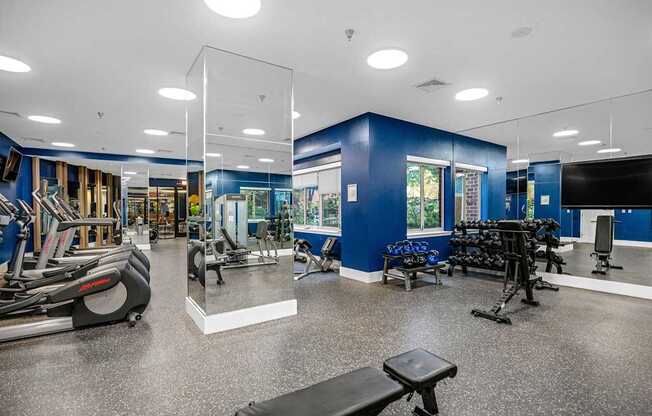 A gym with a variety of equipment including treadmills, weights, and exercise machines.