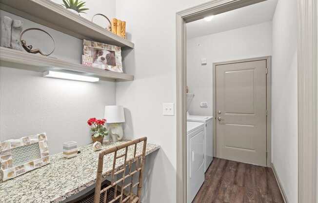 a dining room with a table and chairs and a laundry room in the background