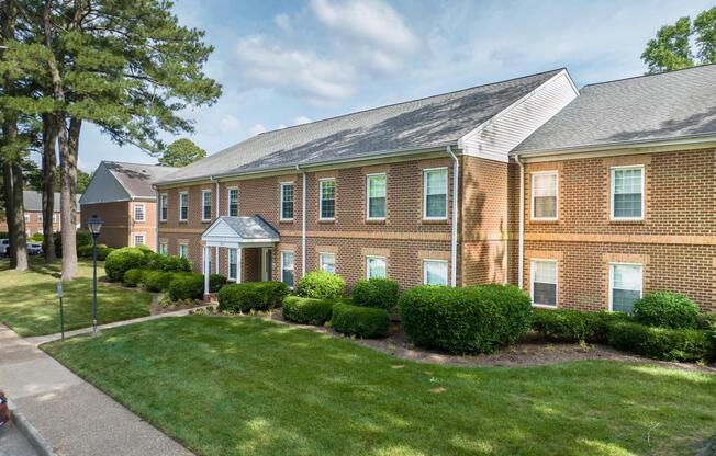 a large brick building with grass in front of a house