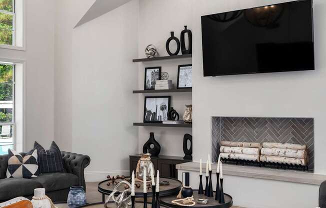 A modern living room with a grey couch, a coffee table, a fireplace, and a TV mounted on the wall.