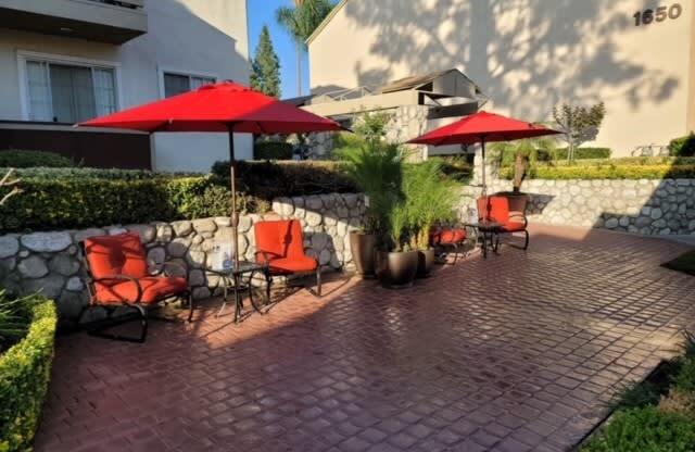 Serene sitting area with brick patio and lush gardens at Northwood Apartments in Upland, California.