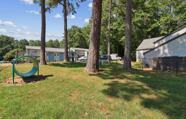 A playground with a green slide and a tree in the foreground.