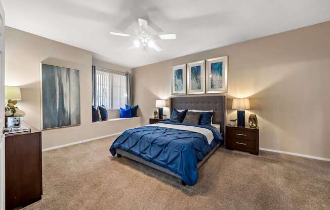 A bedroom with a bed, nightstands, and pictures on the wall.