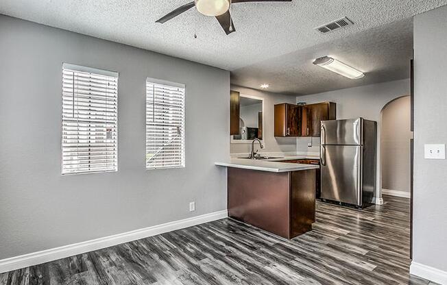 A kitchen with a wooden floor and a stainless steel refrigerator.