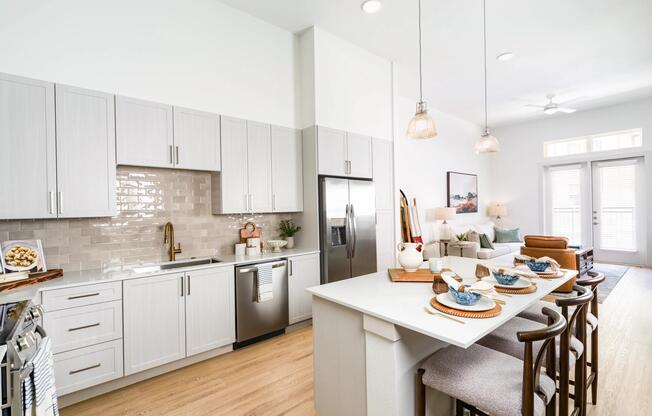 Open kitchen with quartz countertops, pendant lighting, and bar seating flowing into a connected living area filled with natural light.