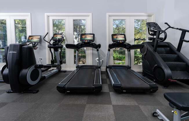 A gym with treadmills, elliptical machines, and a stationary bike.