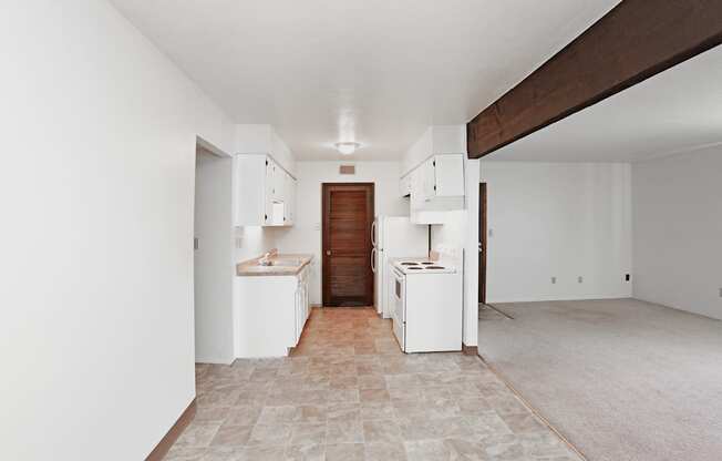 A kitchen area with white appliances and a tiled floor.