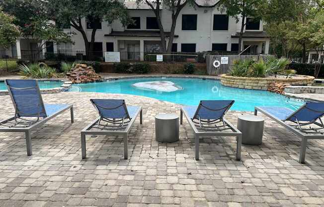 a swimming pool with blue lounge chairs and a resort style pool