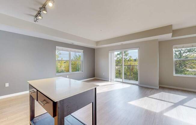 A spacious room with a table and chairs in the foreground and sliding glass doors leading to a balcony.