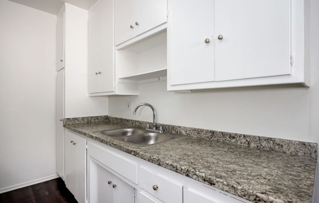 a kitchen with white cabinets and granite counter top and a sink