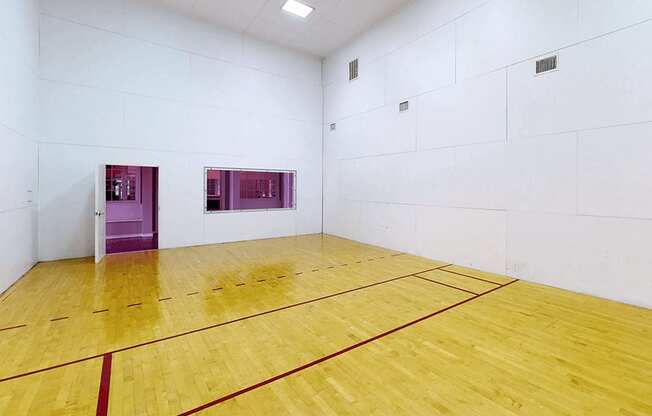 a Raquetball court with a wooden floor and white walls