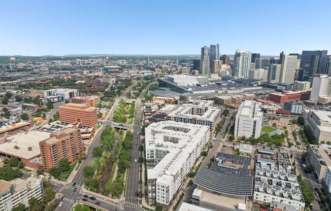 A cityscape with a mix of modern and older buildings, a clear sky, and a busy intersection.