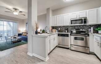 spacious kitchen with stainless steel appliances and white cabinets in an apartment