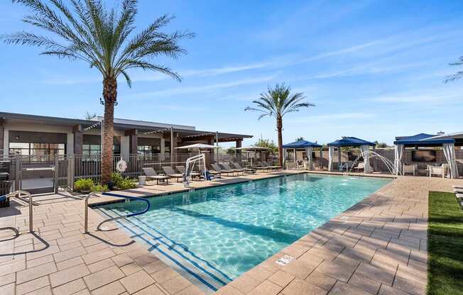 A swimming pool surrounded by palm trees and lounge chairs.