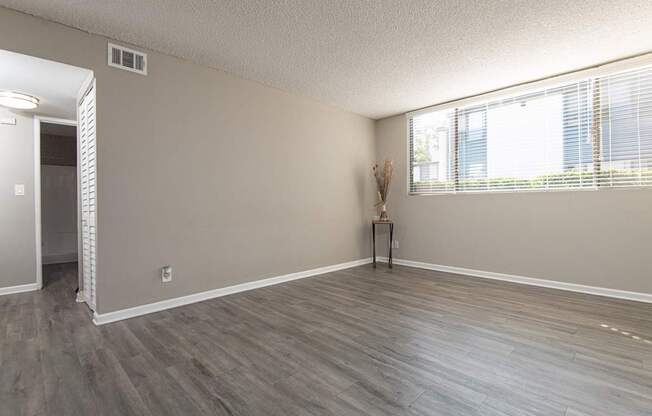 A room with a wooden floor and a window with blinds.