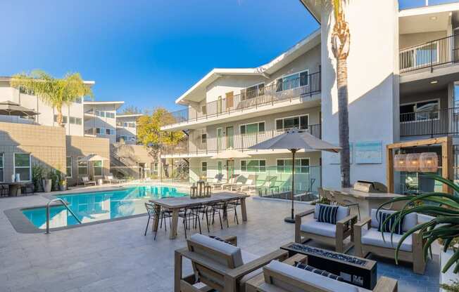 a swimming pool with a table and chairs in front of a building