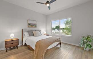 A bedroom with a bed, nightstand, and a potted plant.