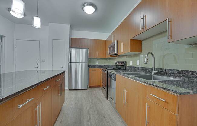 A kitchen with wooden cabinets and a granite countertop. at Vue Greenville, Dallas, TX