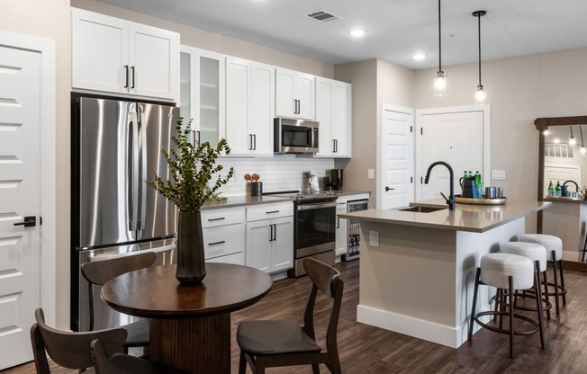 a kitchen with white cabinets and a table with chairs