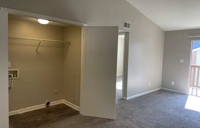 A room with a carpeted floor and a closet with a shelf.