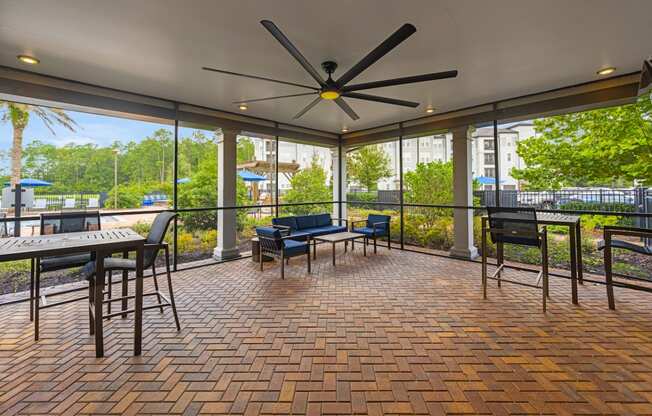 a covered patio with tables and chairs and a ceiling fan