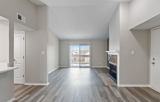 an empty living room with a fireplace and a door to a balcony