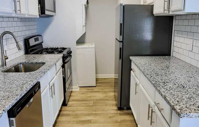 an empty kitchen with white cabinets and a black refrigerator