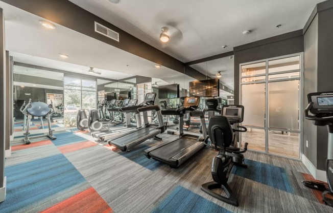 a gym with weights and cardio equipment on the floor and a glass door
