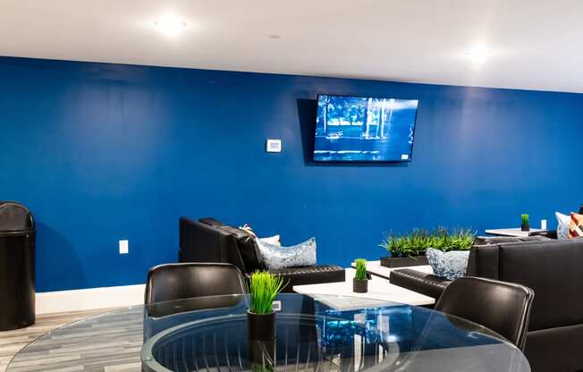 a living room with a blue wall and a glass table and chairs