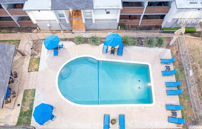 a resort style pool with blue umbrellas and chairs around it