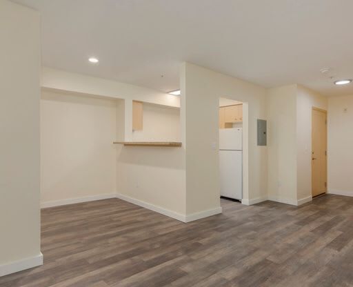 an empty living room with a kitchen in the background