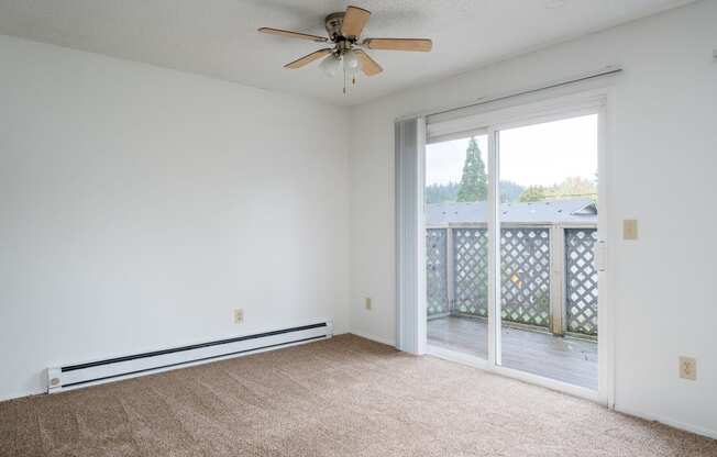 an empty living room with a ceiling fan and a balcony