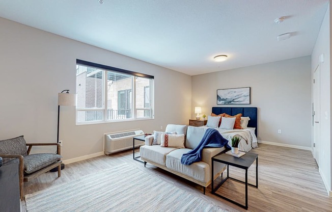a living room with a couch and chair and a bed with a blue headboard