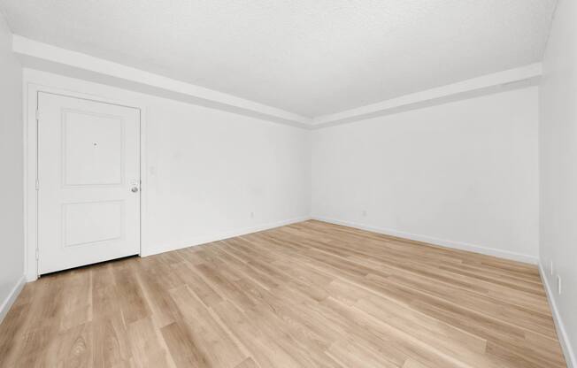 an empty room with white walls and wood flooring