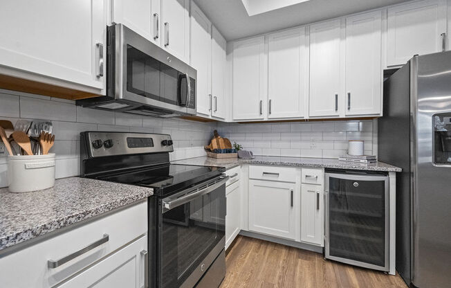 a kitchen with white cabinets and stainless steel appliances including a wine refrigerator