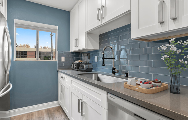 Blue tiled kitchen with stainless steel fridge and dish washer.