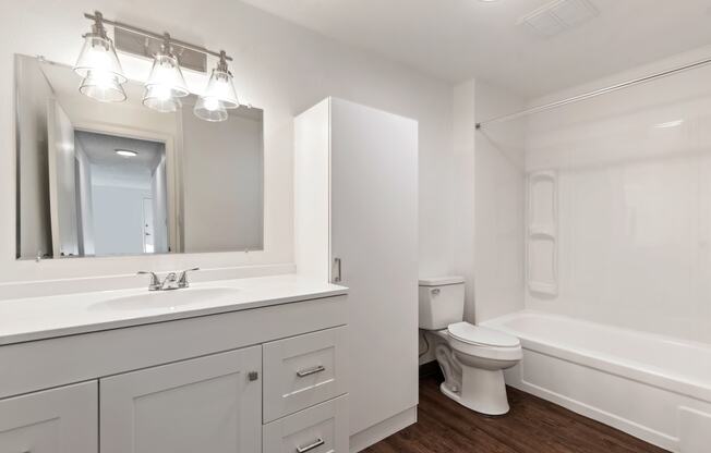 a bathroom with white cabinets and a toilet and a sink