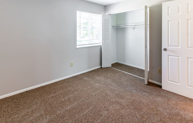 an empty room with carpet and a window and a closet