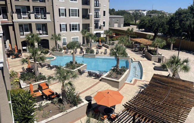 A pool surrounded by palm trees and chairs.