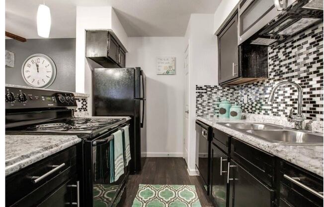 a kitchen with black appliances and a clock on the wall