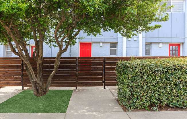 a wooden fence in front of an apartment building with a red door