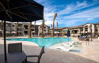 A pool area with a table and chairs and umbrellas.