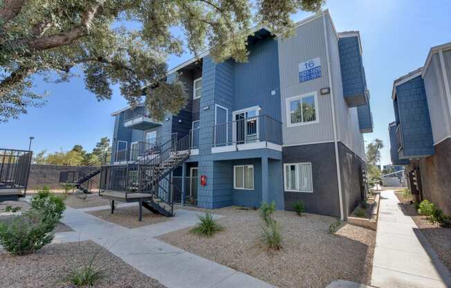 a blue apartment building with stairs and a sidewalk