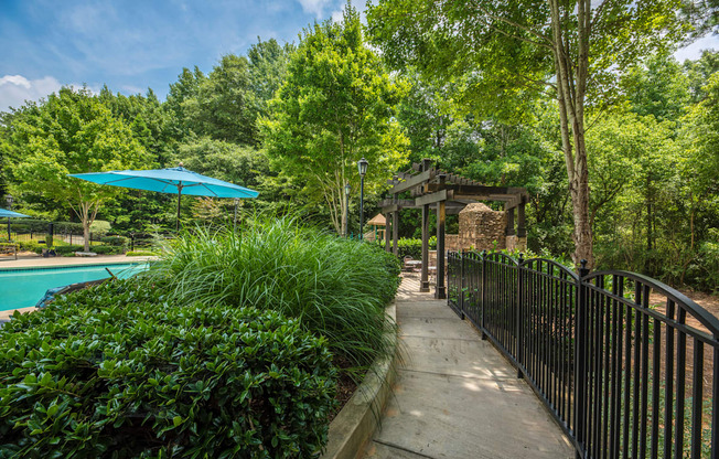 a walkway next to a pool with a gazebo and a fence