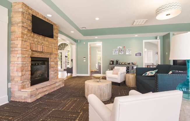 Resident lounge area with couches facing a fireplace and TV at Angel Landing Apartment Homes in Pensacola, FL